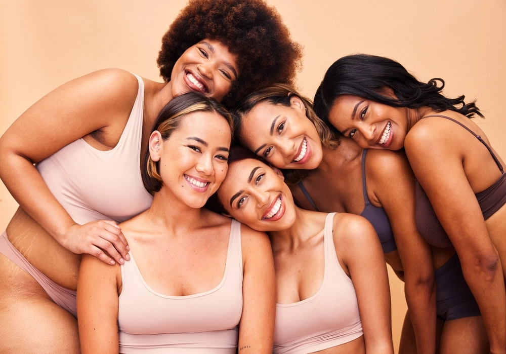 Diversity and women with beauty, wellness and body positivity on a beige studio background. Models, friends or group with self love, inclusion and support with skincare, aesthetic and smile